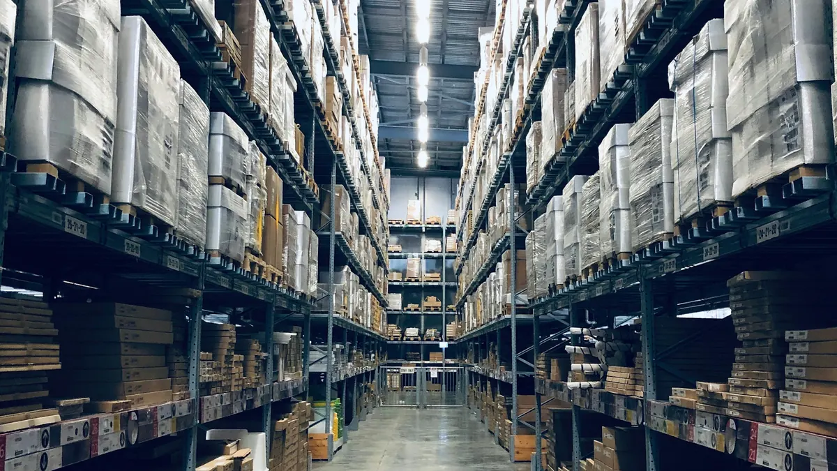 Allée d'un entrepôt aux rayonnages chargés de cartons et de palettes