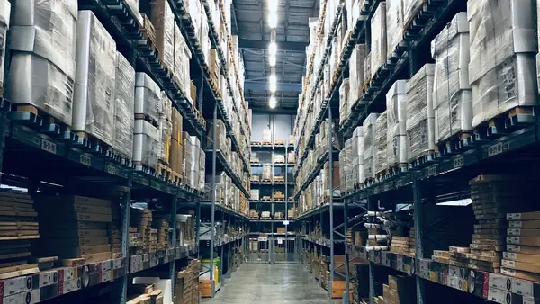 Allée d'un entrepôt aux rayonnages chargés de cartons et de palettes