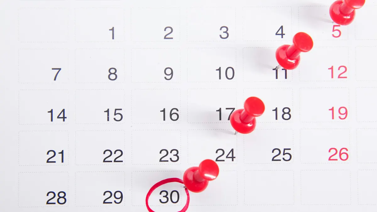 Calendrier mensuel avec des punaises rouges marquant des dates