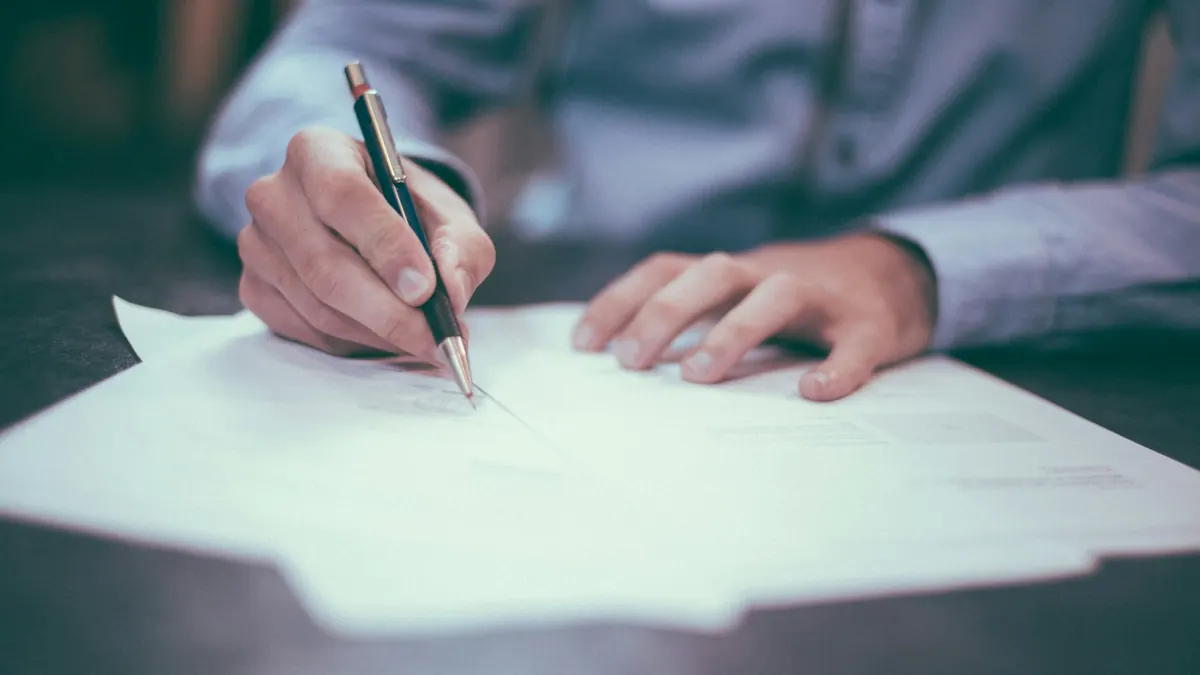 Main signant un document au stylo