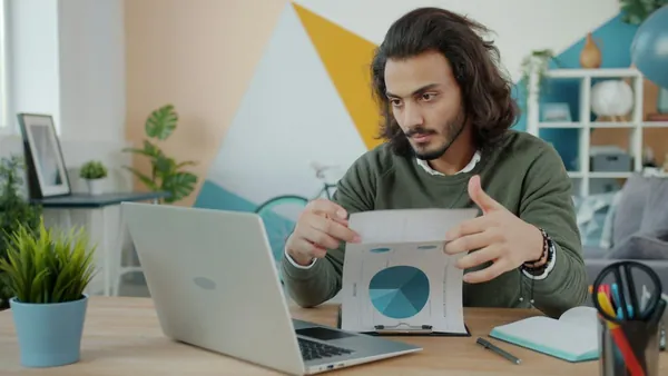 Dirigeant examinant un document devant son ordinateur portable
