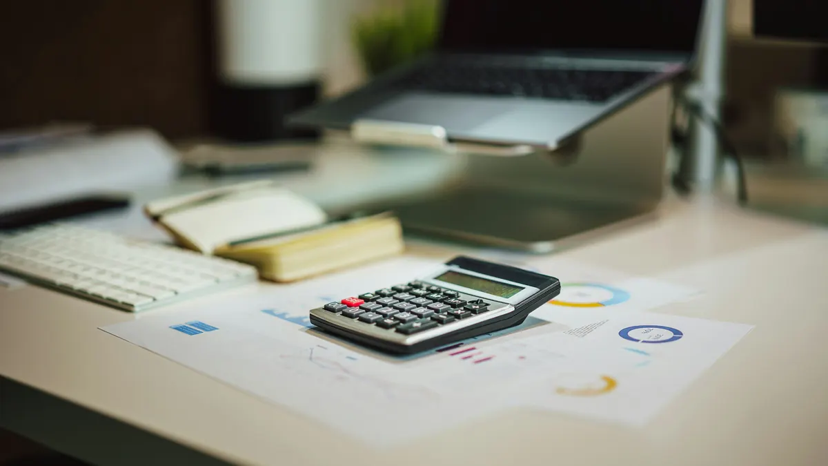 Calculatrice posée sur des graphiques financiers imprimés, sur un bureau
