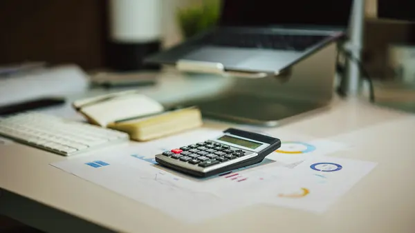 Calculatrice posée sur des graphiques financiers imprimés, sur un bureau